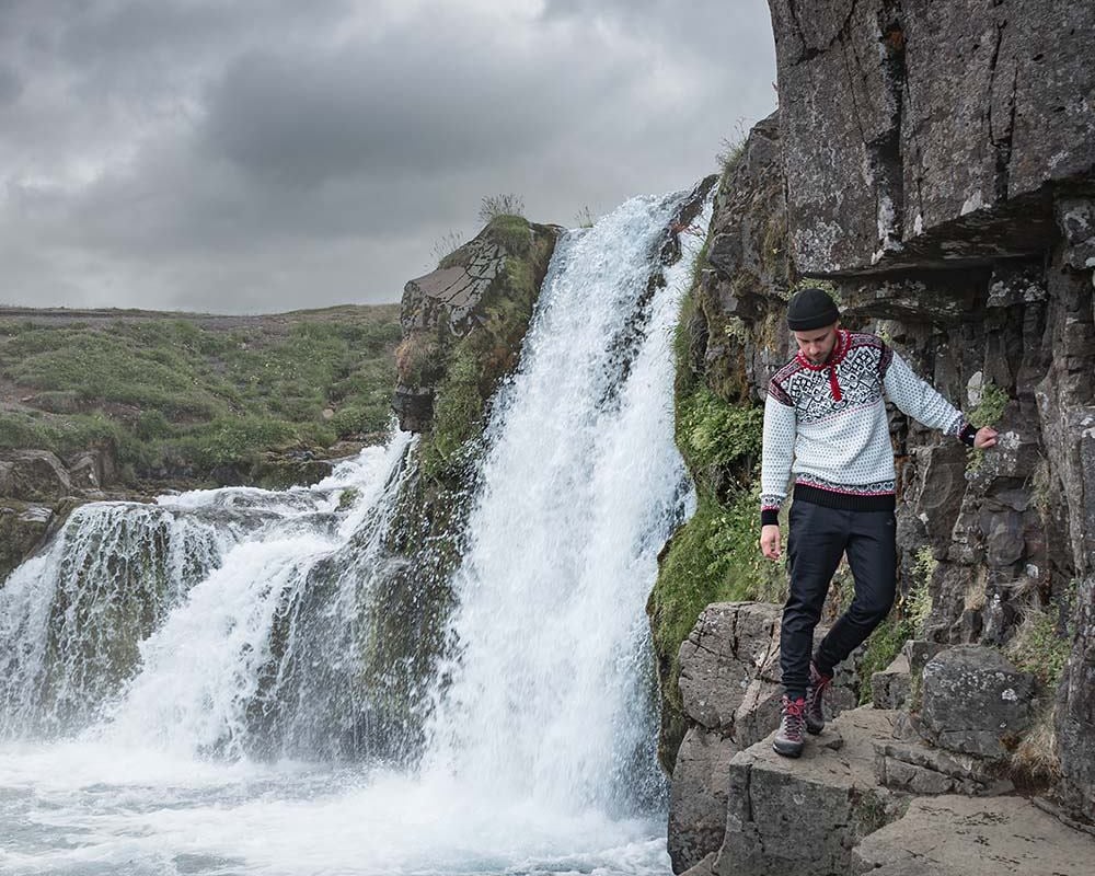 man walking next to waterfall