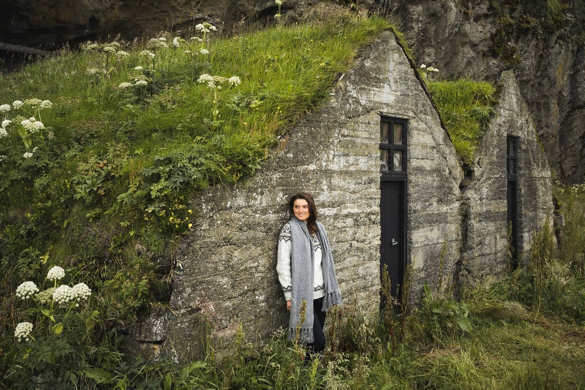 Frau an einem alten Haus mit Grasdach