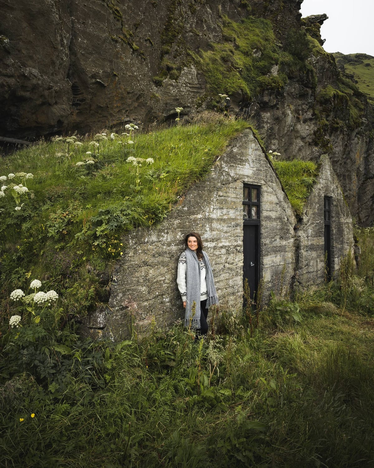woman standing next to old Icelandic house with grass roof
