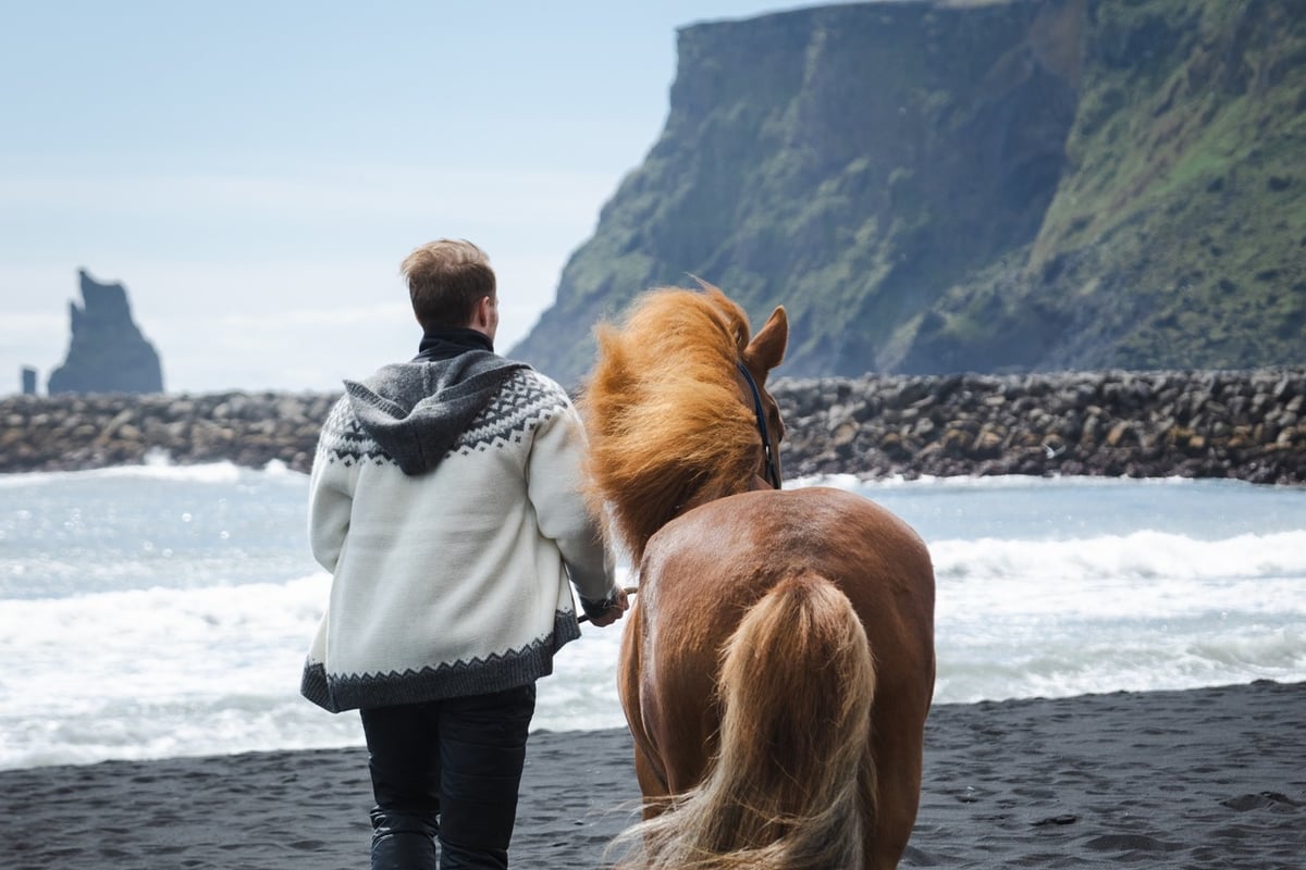 Mann und Pferd am Black Beach, Südisland