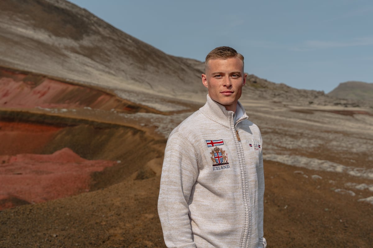 man and red sand mountain behind him