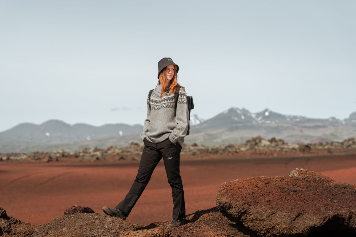 Une femme sur le sable rouge, l’ouest de l’Islande et les montagnes derrière elle