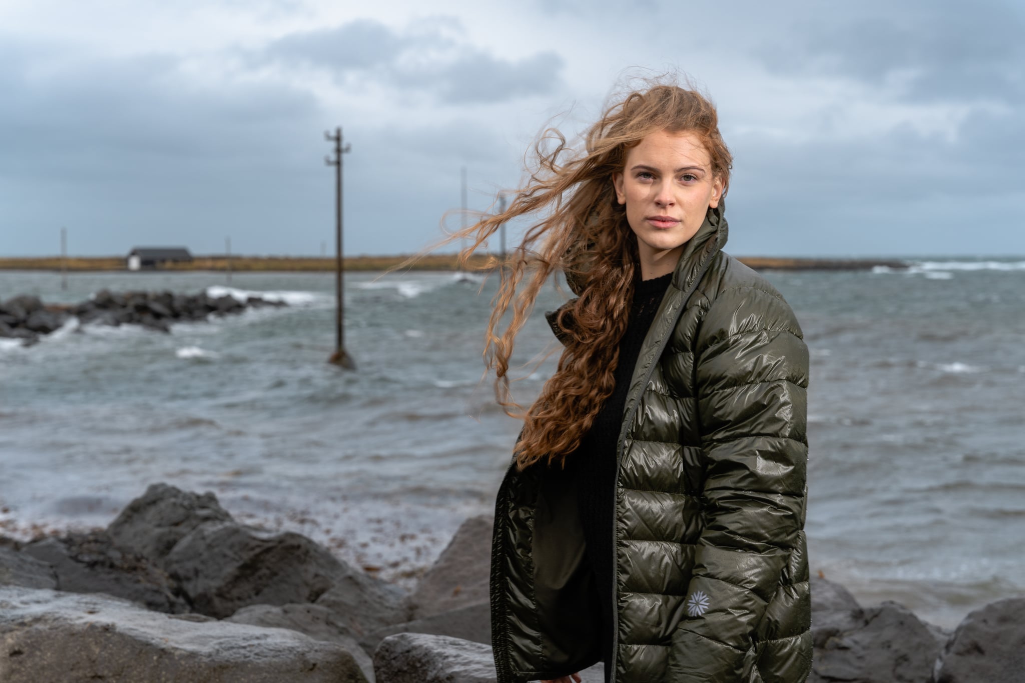 woman-standing-seashore-darkgreen-puffer-jacket.jpeg
