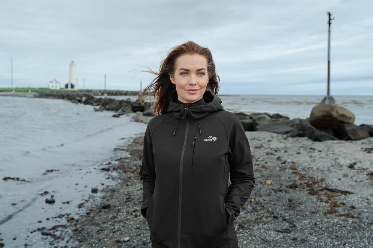 woman walking on the beach and lighthouse behind her