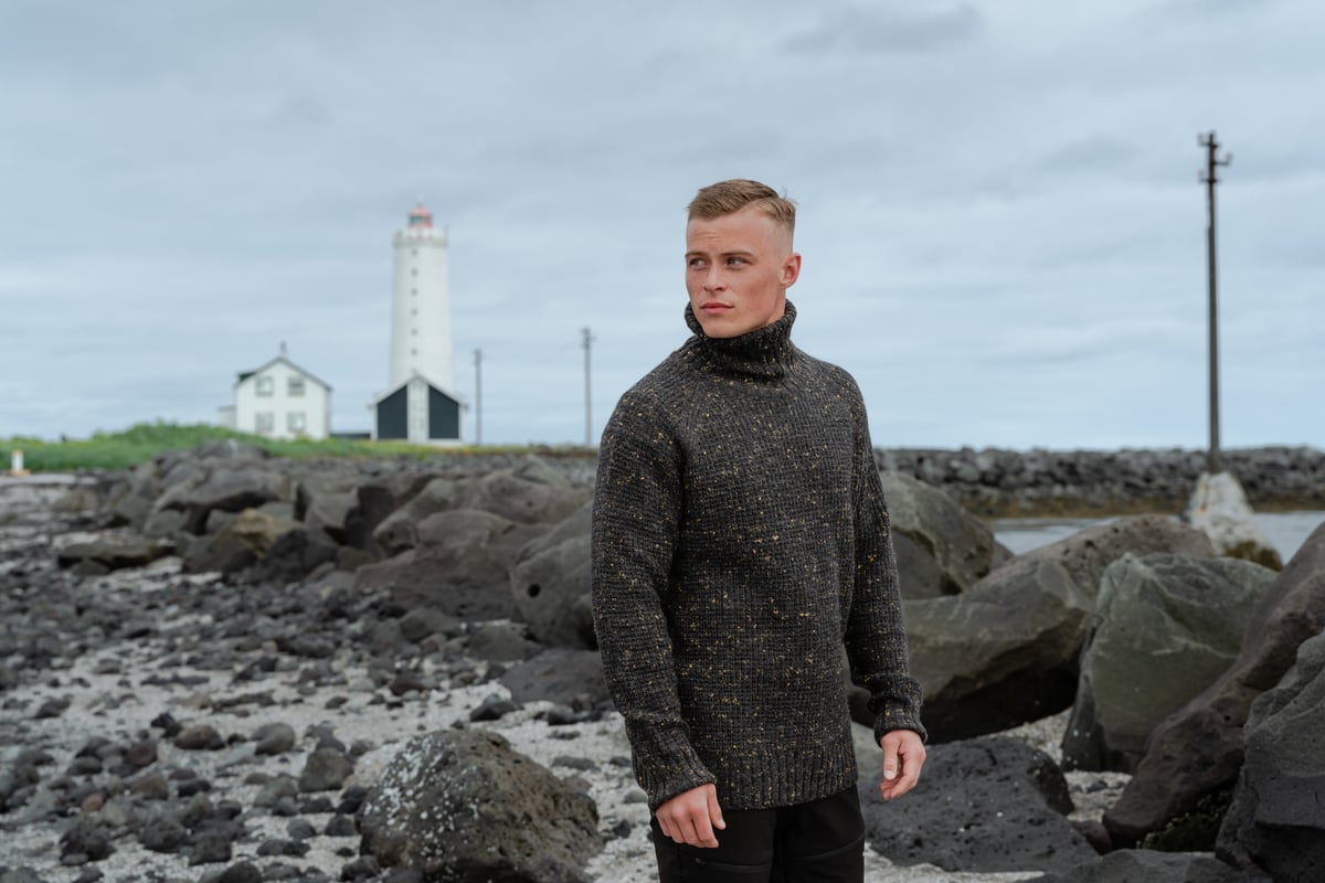 Un homme au bord de la mer, un vieux phare derrière lui