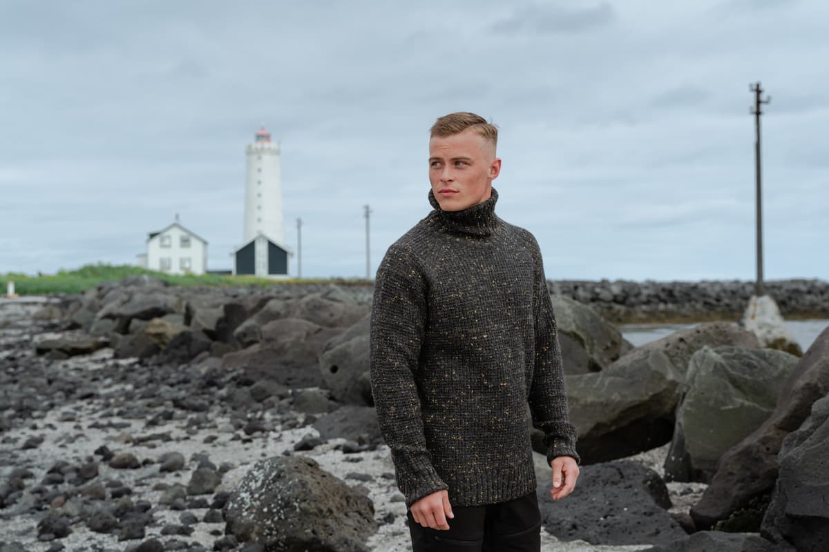 Un homme au bord de la mer, un vieux phare derrière lui