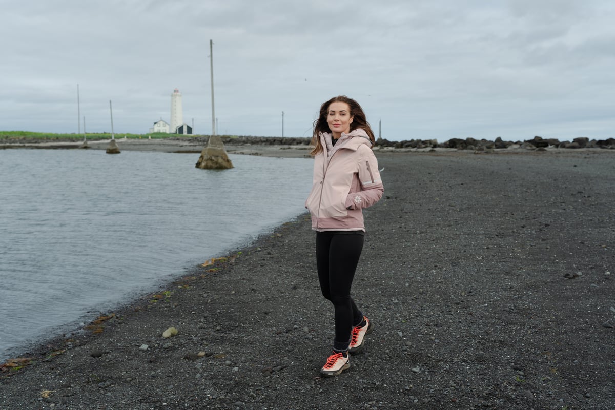 woman walking on the beach with old light house behind her