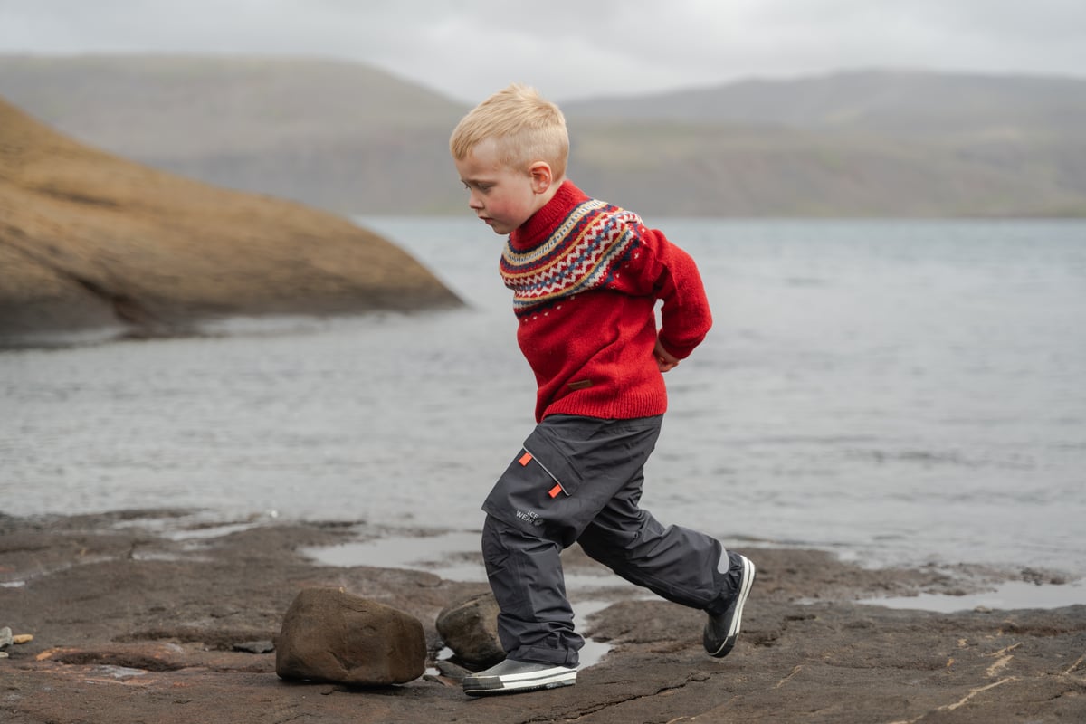 Boy running on a cliff next to a lake