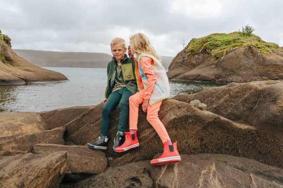 girl whispering something to a boy, on a rock by a lake