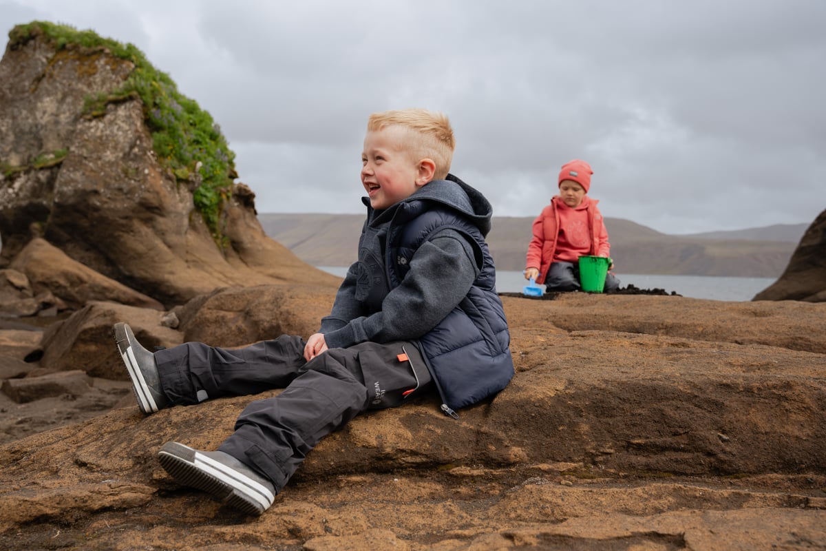 boys playing on a cliff next to a lake