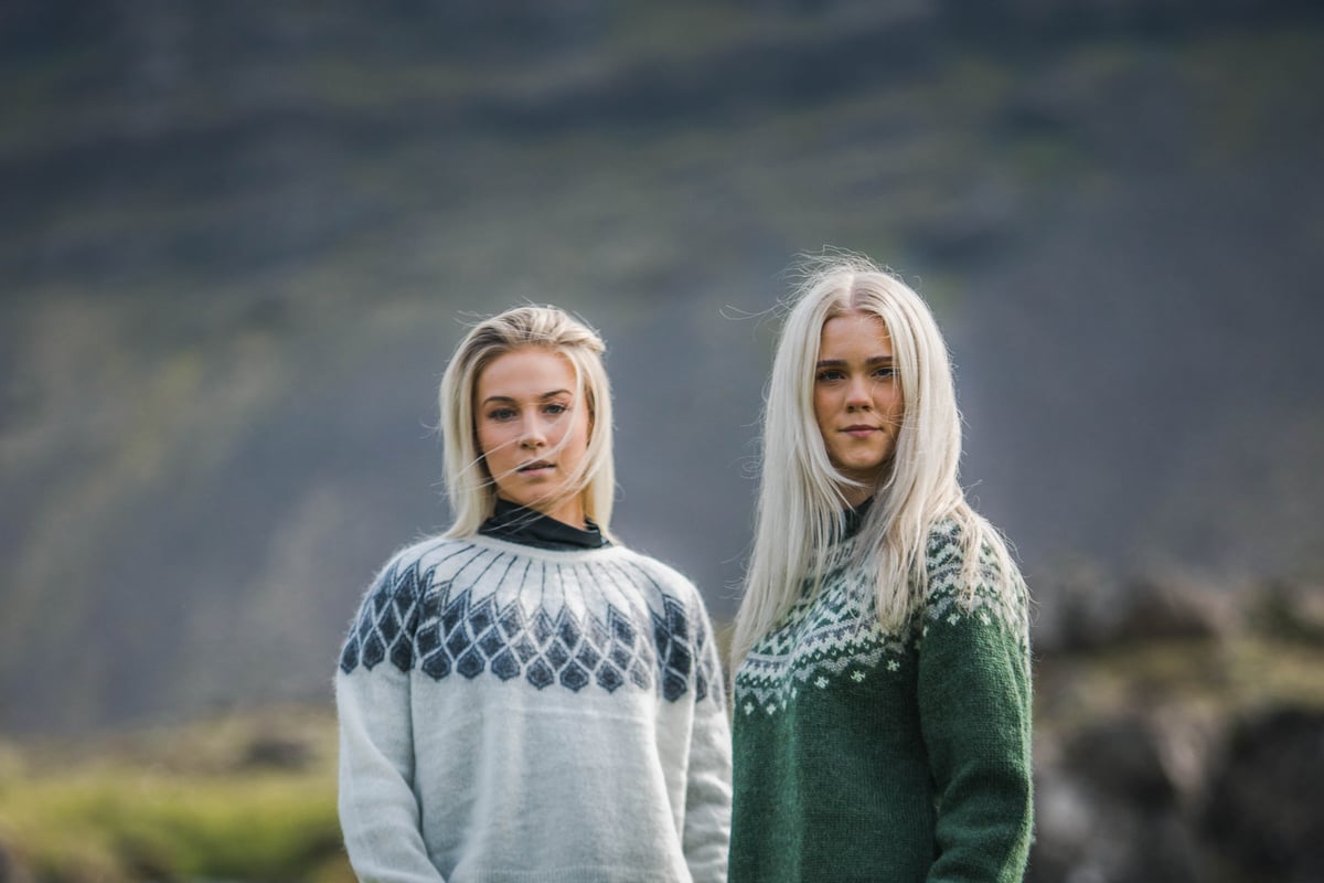 two woman in Icelandic nature, green gras and waterfall behind them