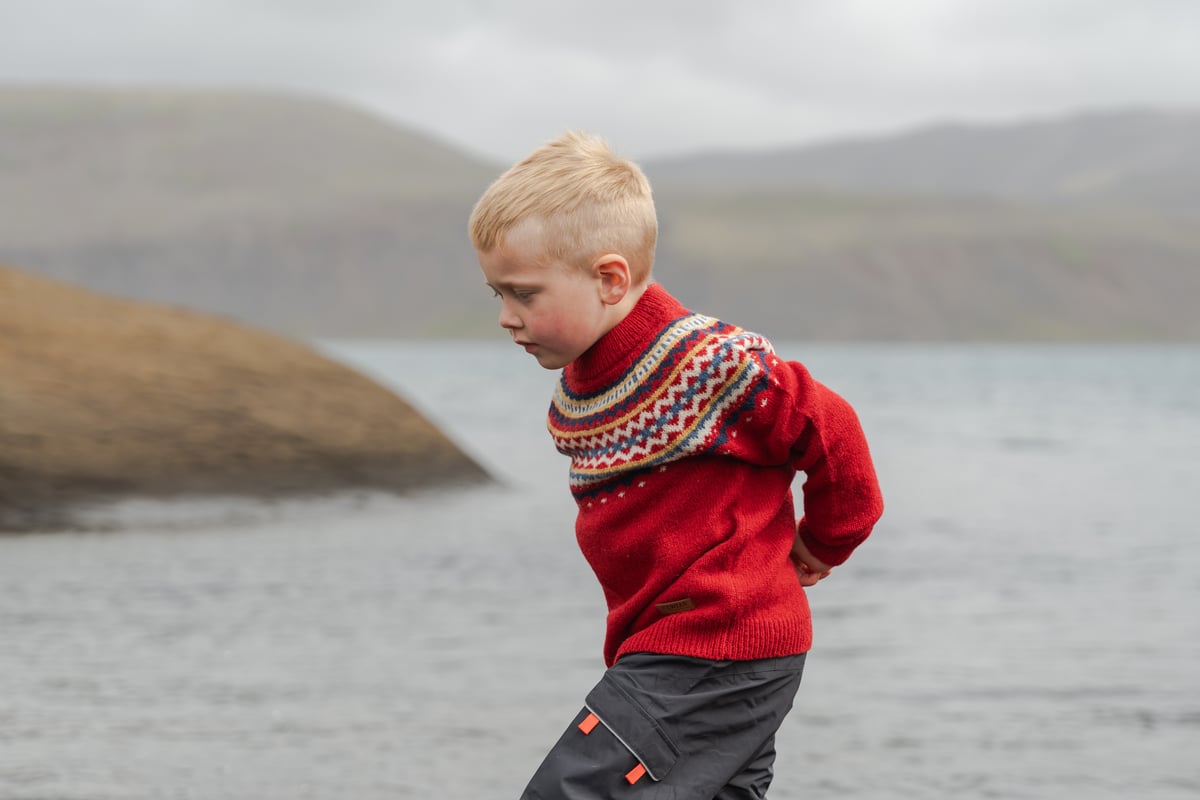 Boy running on a cliff next to a lake