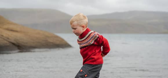 Boy running on a cliff next to a lake
