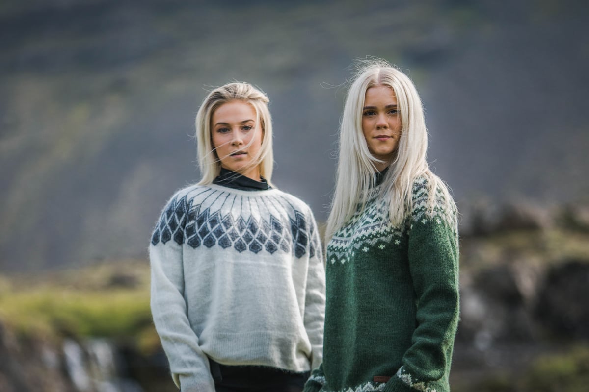 two woman in Icelandic nature, green gras and waterfall behind them
