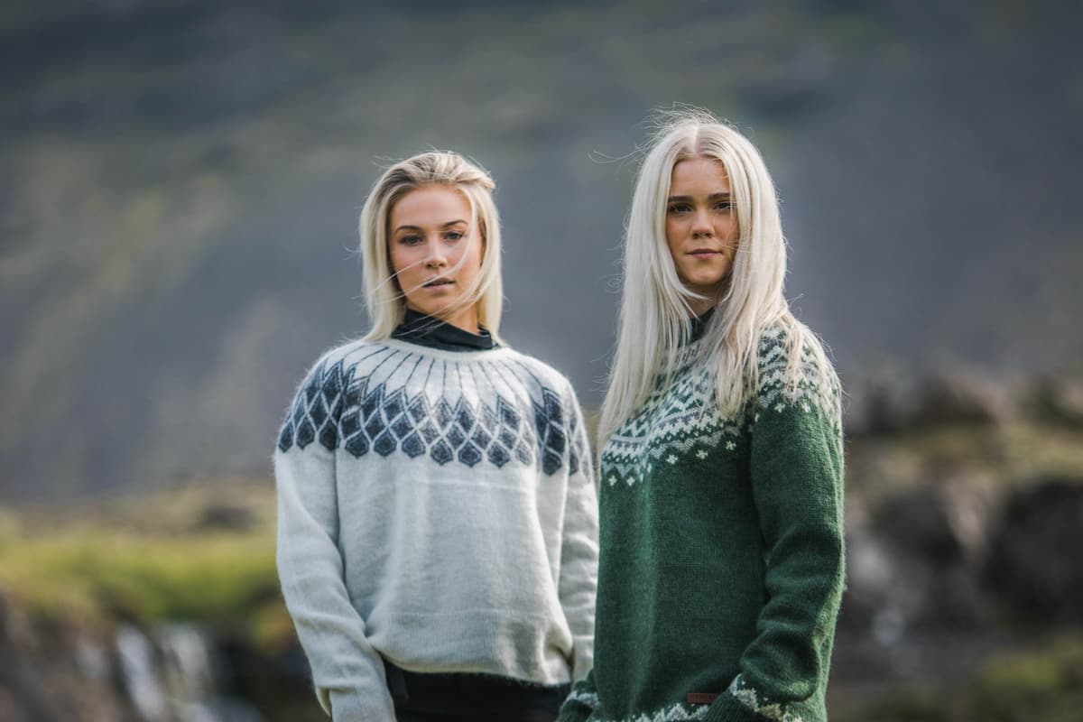 two woman in Icelandic nature, green gras and waterfall behind them